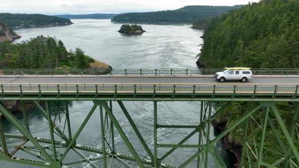 Panning aerial shot of a truck driving over the bridge at Deception Pass.