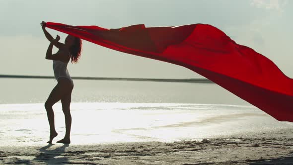 Fluttering Red Fabric in the Hands of a Young Woman on the Beach, Vacation, 