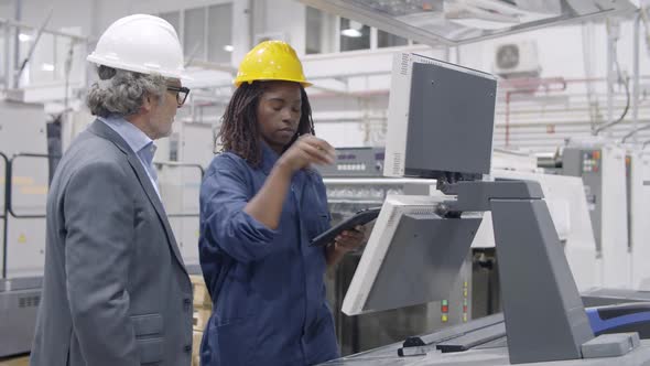 Black Female Industrial Professional Standing at Control Panel