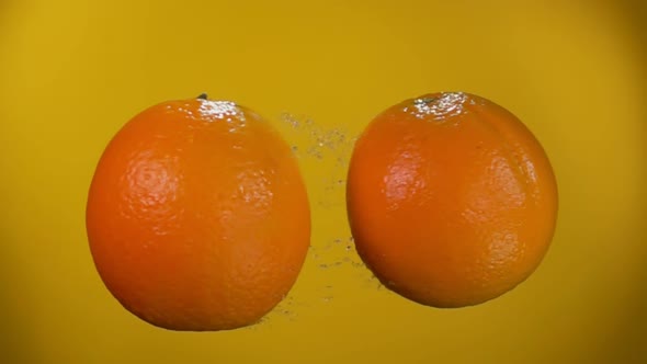 Oranges Are Colliding with Each Other Rising Drops of Water on Yellow Background