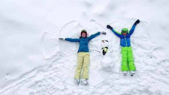 Woman and a Boy Lay in the Snow Waving Hands View From Above