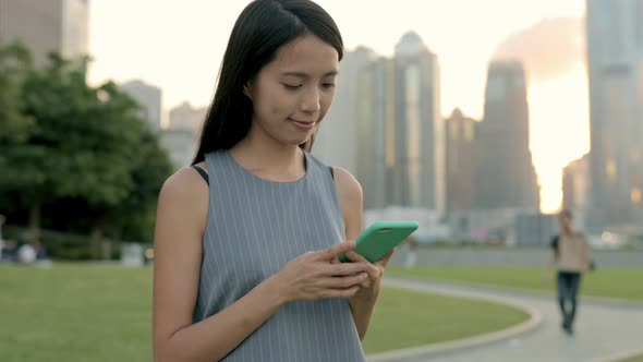 Business woman use of cellphone under sunset at hong kong