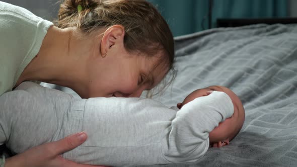 Mother Tickles Newborn Son Making Baby Boy Laugh Loudly