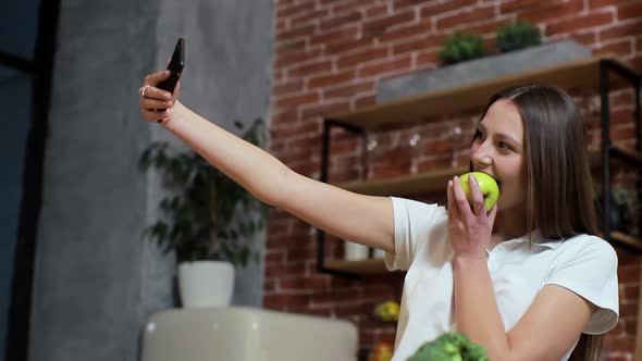 Woman Browsing on Mobile Phone at Home Kitchen. Young Woman Browsing on Smartphone Smiling Happy. A