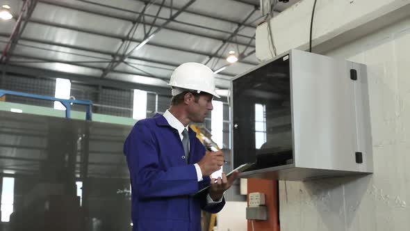 Mature Man Inspecting Equipment in Factory