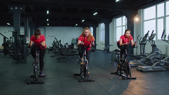 Group of Girls Performs Aerobic Training Workout Cardio Routine on Bike Simulators Cycle Training