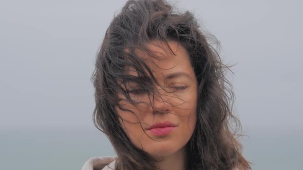 Portrait of Smiling and Laughing Blue Eyed Woman at the Beach Enjoying the a Rainy Day