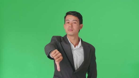 Happy Asian Business Man Showing Thumbs Up And Thumb Down Gesture In The Green Screen Studio