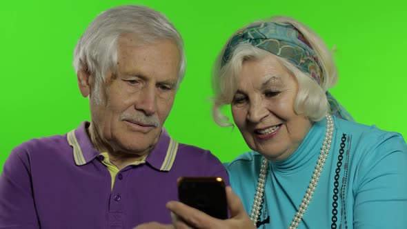 Mature Senior Old Couple Grandparents Enjoy Online Shopping on Mobile Phone