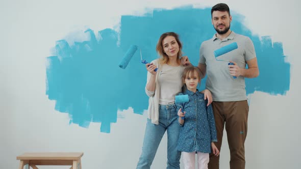 Slow Motion Portrait of Happy Family Mother Father and Daughter Holding Painting Rollers Indoors at