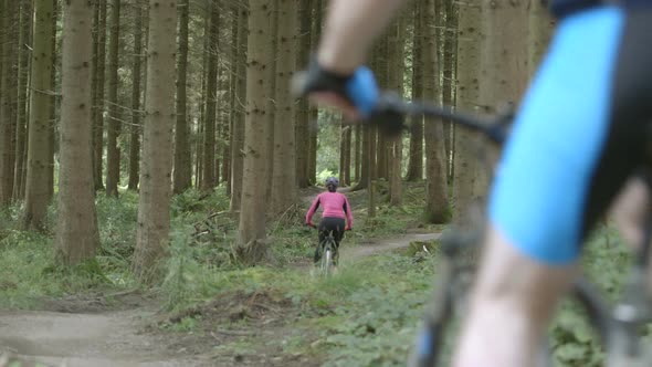 Couple cycling through forest Tracking Left