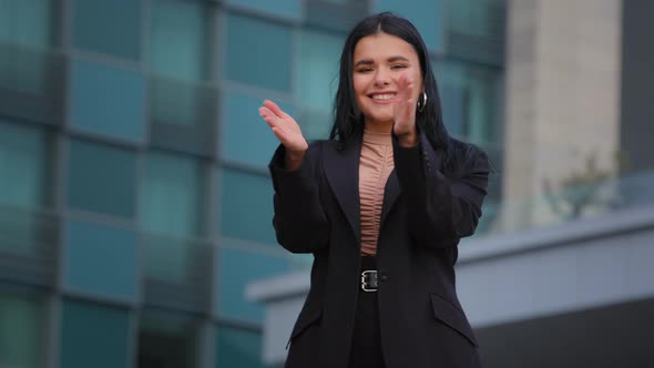 Young Successful Smiling Hispanic Business Woman Clapping Hands on Background Office Building