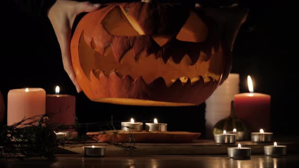 Halloween Pumpkin Head Jack-o-lantern with Burning Candles Over Black Background