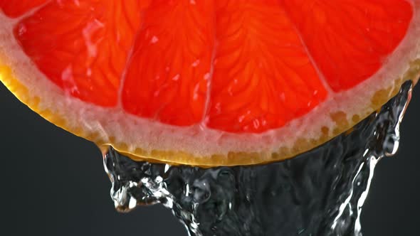 Super Slow Motion Macro Shot of Flowing Water From Grapefruit Slice on Black Background at 1000Fps