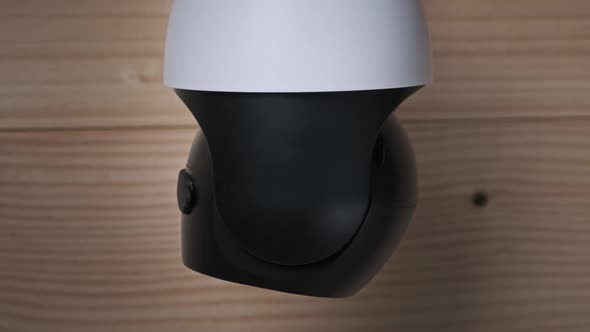 Security Camera Surveillance Rotates on Wooden Background