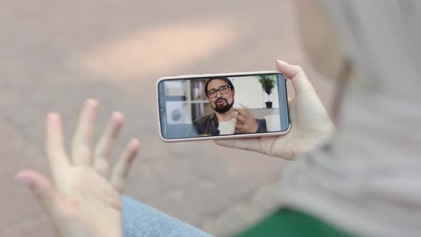 Young Muslim Woman Resting at Park with Digital Smart Phone Having a Video Call with Her Husband