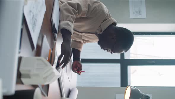 Afro-American Male Architect Using Computer and Taking Notes