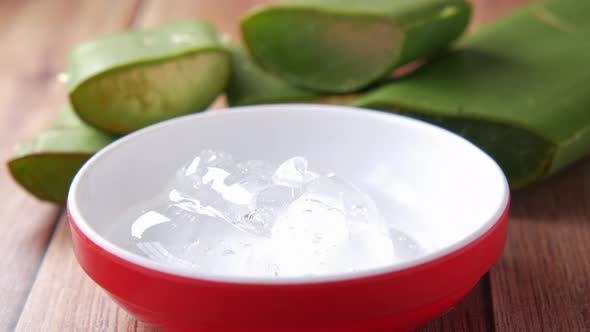Fresh Aloe Vera Sliced and Liquid Gel in Plastic Container on White Background