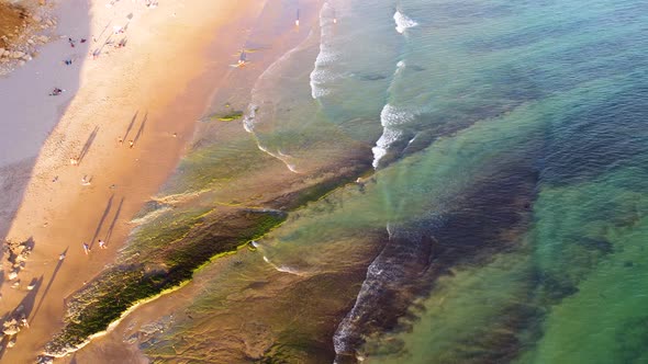 Amazing scenic drone aerial view of the beach and ocean with calm waves during a sunset