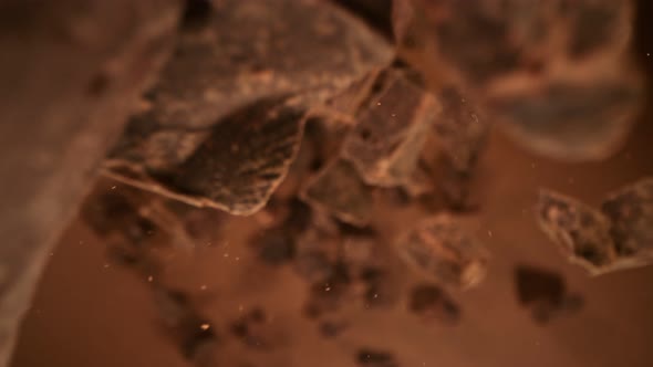 Super Slow Motion Detail Shot of Falling Raw Chocolate Chunks on Brown Background at 1000Fps