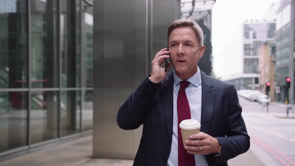 Businessman walking to work on phone with takeaway coffee