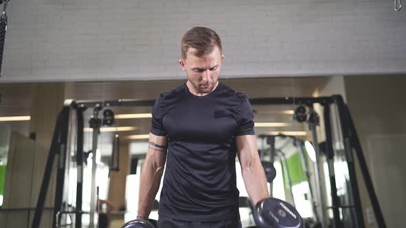 Young Man in Sportswear Lift Weights While Working Out in Gym.