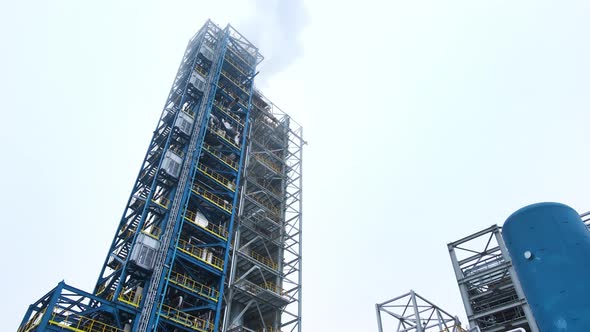 Tower for distillation of oil and gasoline. Steel pipelines at an oil refinery