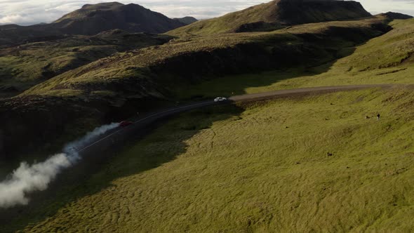 View Of Cars Drifting Battle On Asphalt Race Track At Mountains With Smoke From Tires During Summer.