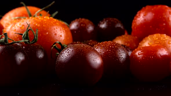 Cherry tomatoes on a black background in water drops.