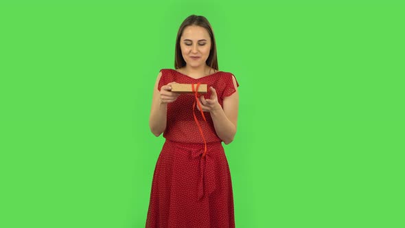 Tender Girl in Red Dress Is Opening the Gift, Very Surprised and Upset. Green Screen
