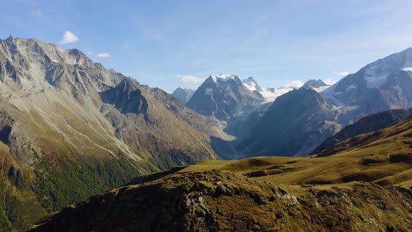 Aerial orbit around mountainous landscape revealing high mountain peaks and glaciersAutumn colors i