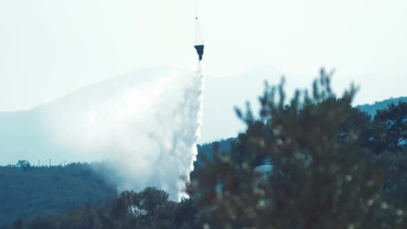 Helicopter flying to forest fire dropping water