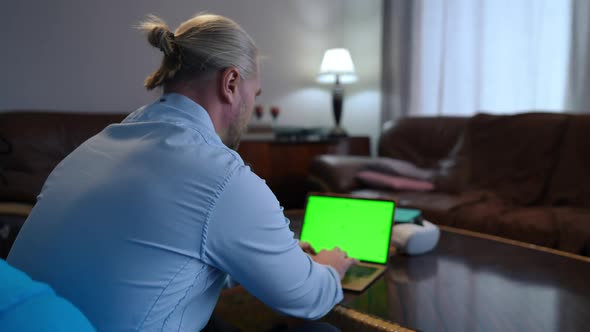 Shooting Over Shoulder of Successful Confident Caucasian Man Messaging Online on Green Screen Laptop