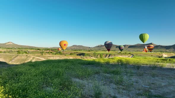 Hot air balloons fly over the mountainous landscape of Cappadocia, Turkey.