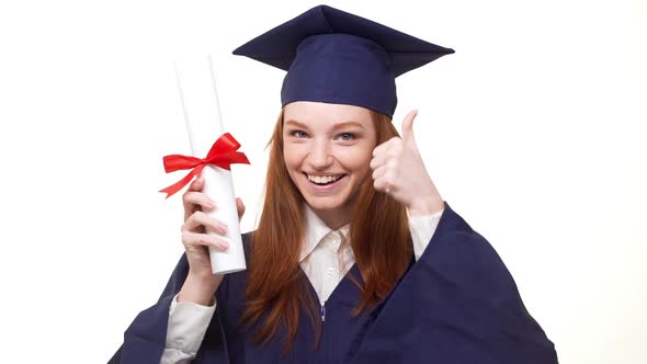 Cheerful Beautiful Ginger Caucasian Girl in Blue Academic Dress Showing Her Diploma with Pride and