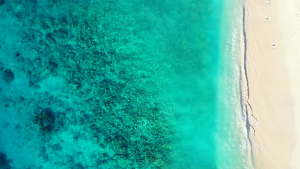 Beautiful turquoise sea texture with coral reef and rocks over white sand of seabed seen through cle