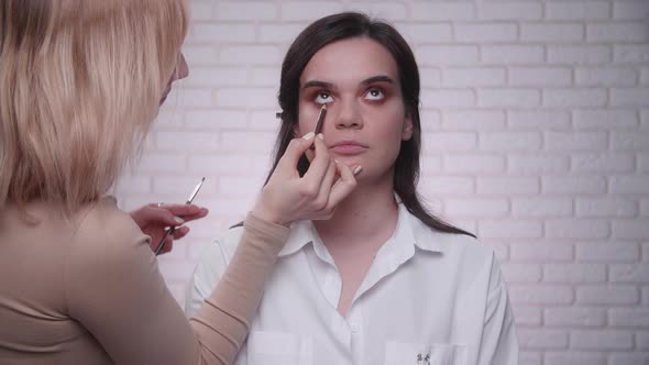 Makeup Artist Wearing Camelcolored Turtleneck Applies Eyeshadow on a Client