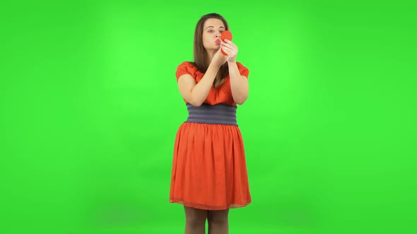 Cute Girl Is Painting Her Lips Looking in Red Mirror. Green Screen