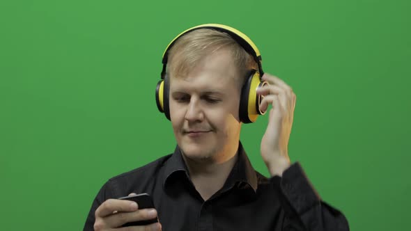 Guy Listens To Music in Wireless Yellow Headphones and Dances. Green Screen