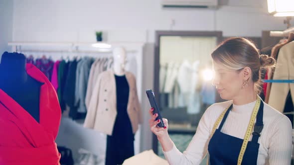 A Dressmaker is Using Her Phone to Take a Photo of Fabric