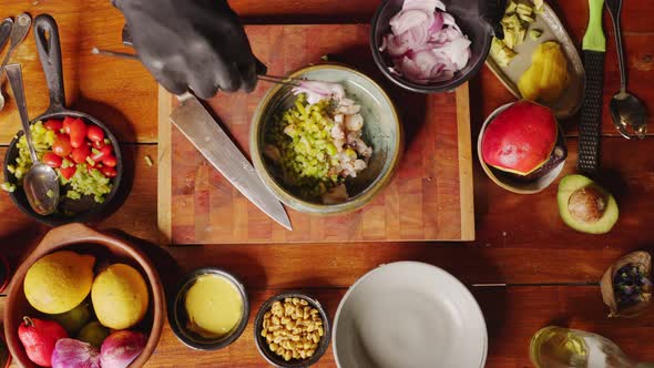 Preparation of Ceviche - table top view of a skilful chef adding fresh red onions and pouring olive