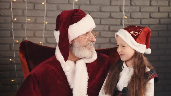 Girl in Red Hat Whispering a Wish To Santa