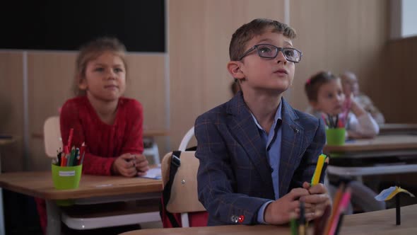 Focused Schoolkids Listening To Teacher in Class