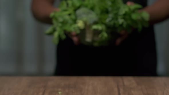 Male hands put a bowl of greens on the table