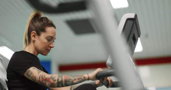 Woman Exercising with Elliptical Cross Trainer at gym.Side View Close-up, Slow Motion. Woman