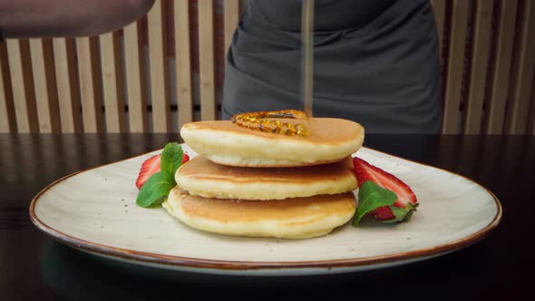 Chef Preparing Pancakes with Maple Syrup and Sugar Powder