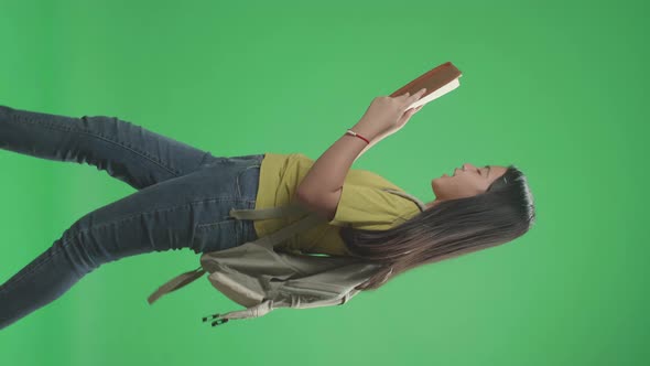 Asian Girl Student Holding And Looking Book While Walking To School On Green Screen Chroma Key