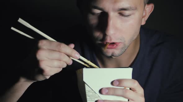 Close-up of a Man Who Is Eating Noodles with Chopsticks From a Box. European Eating Chinese Food