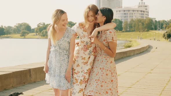 Three young beautiful girls posing outdoors at summer sunny day