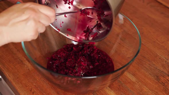 Woman Prepares Cold Beetroot Soup in Glass Bowl on Wooden Table